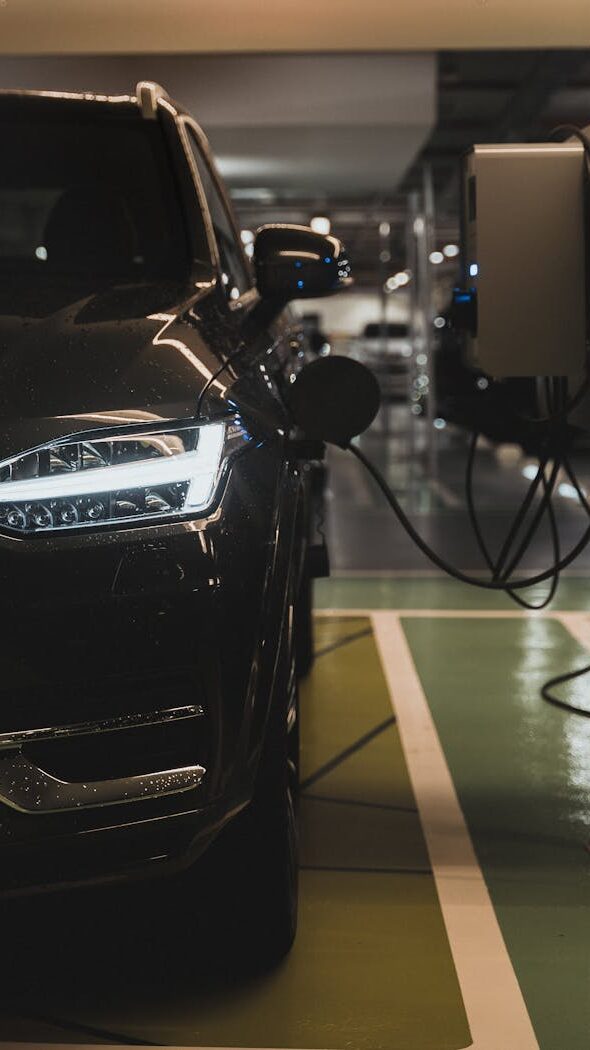 Luxury electric car charging at a station in Curitiba parking garage.